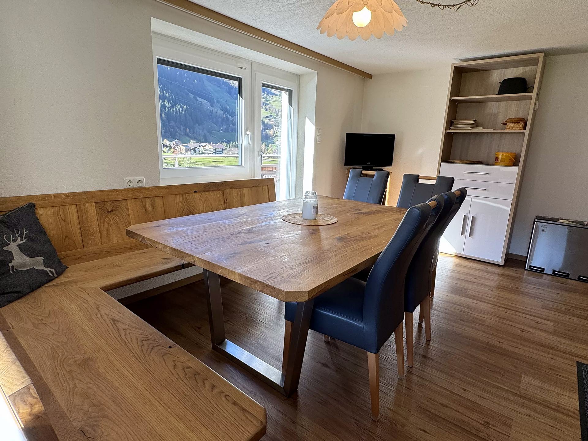 Living and dining area with corner bench, wooden table and valley view